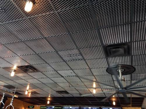 Expanded metal ceiling tiles with diamond holes are installed on the ceiling where lights and fans are installed in the basement.