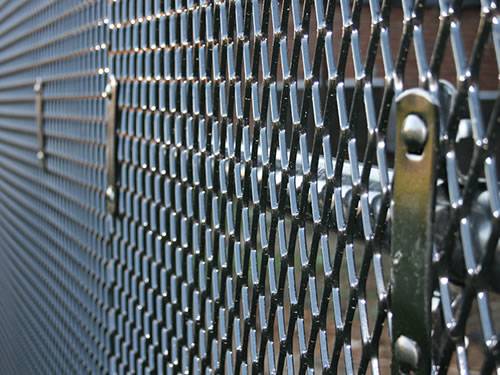 Black raised expanded metal panels with diamond holes are installed on the fencing with screws