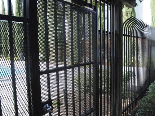 Black raised expanded metal panels with diamond holes and ornamental pickets are used for security fence.