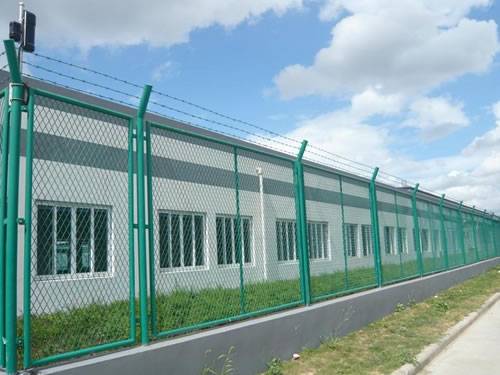 Green expanded metal panels with diamond holes are installed on the security fence in the perimeters of prison and barbed wires are on the top.