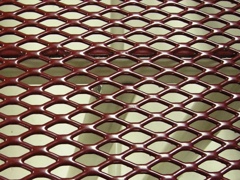 Red expanded metal sheet details with square holes and flattened surface.